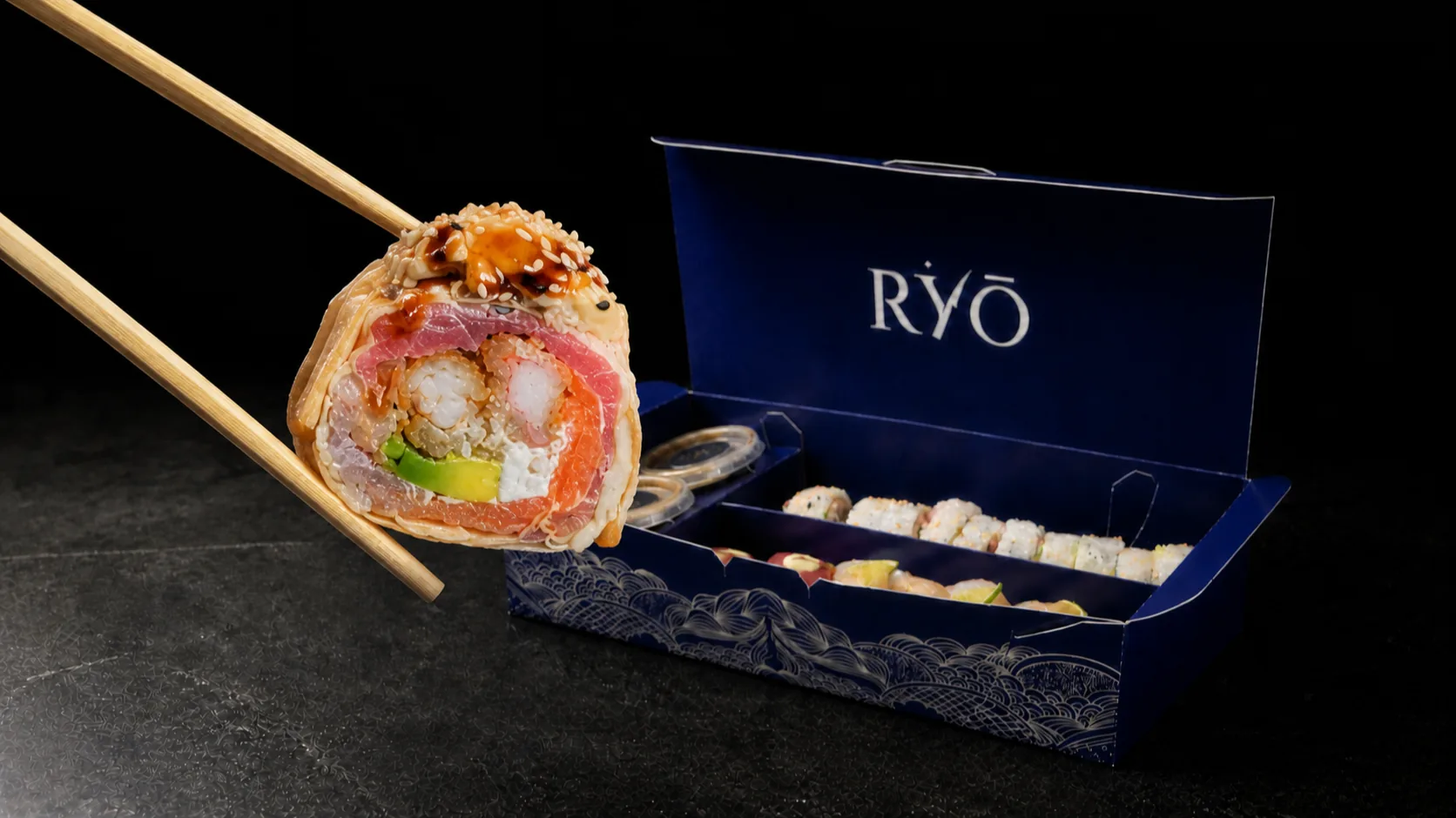 Roll Kamasutra sostenido con palillos frente a la caja azul RYŌ